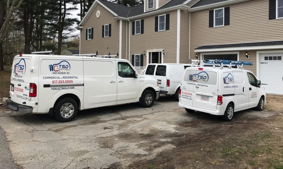 Two TSD Electric service vans parked in a driveway outside a house